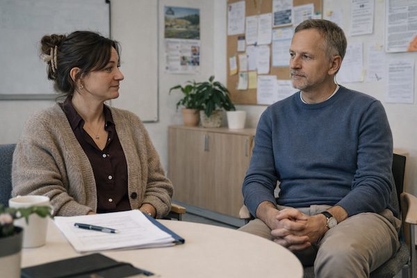 Kommunikation im Kollegium: Konflikte lösen, Beziehungen stärken, souverän führen 5 Zwei Personen im ruhigen Beratungsgespräch an einem runden Tisch in einem Lehrerzimmer.