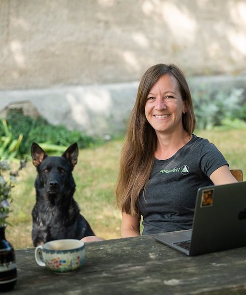 Michaela Heidig, author of the self‑reflection book for teachers “My Ego Is on Holiday”, working outdoors with her laptop and dog.