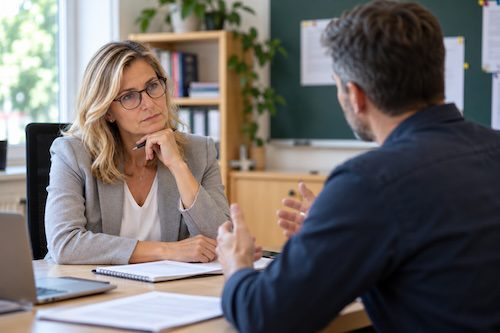 Schulleitung und Lehrkraft in einem ernsten Gespräch in der Schule